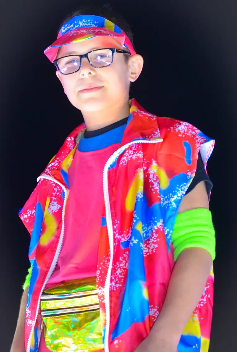 Boy in a bright neon jacket, cap and bum bag posing on a carnival float