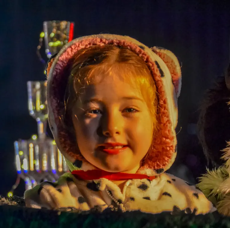 Young child wearing a dalmatian puppy hood smiling on a float at night