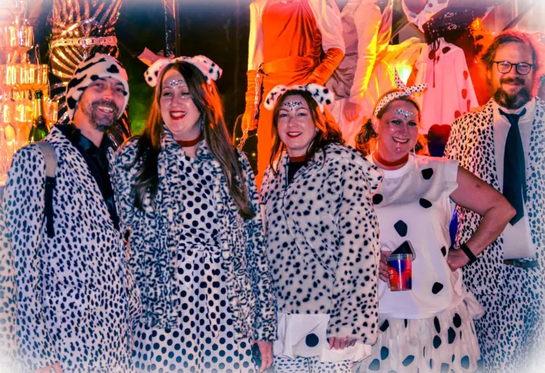 Group of adults dressed in dalmatian print coats and spotty ears at the evening carnival