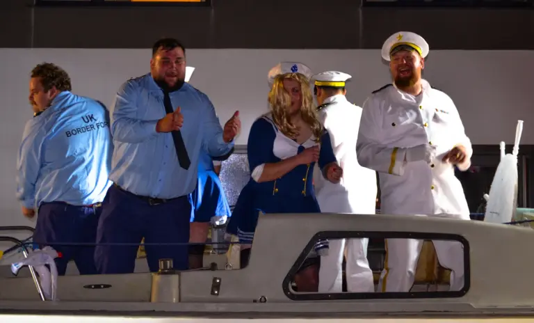 Carnival entrants in Border Force and naval uniforms performing aboard a boat float