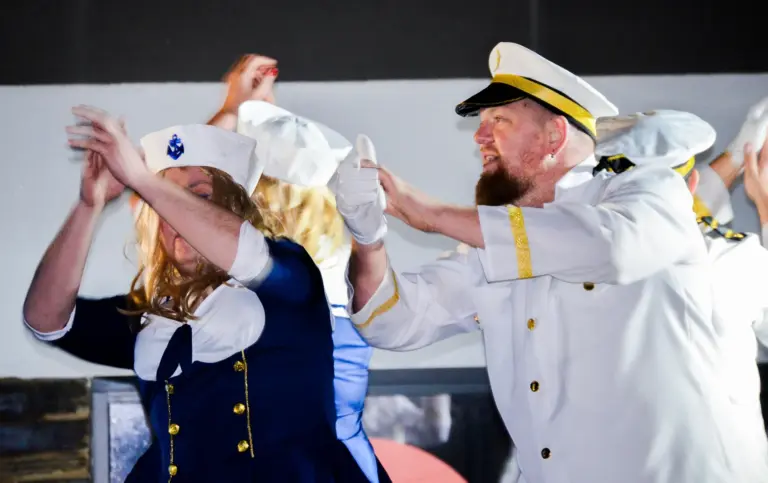 Costumed sailor girls and a bearded captain dancing on the Border Force boat float