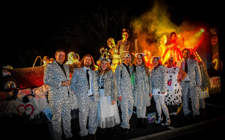Group in dalmatian print suits in front of a smoky, fire-lit float