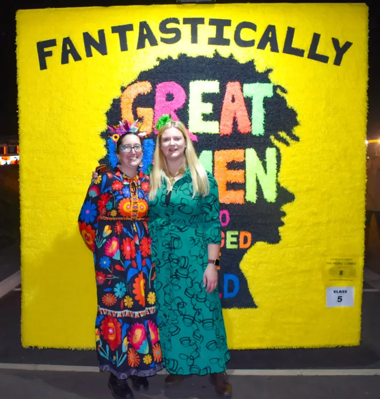 Two women in front of the yellow Fantastically Great Women Who Changed The World crepe-paper float
