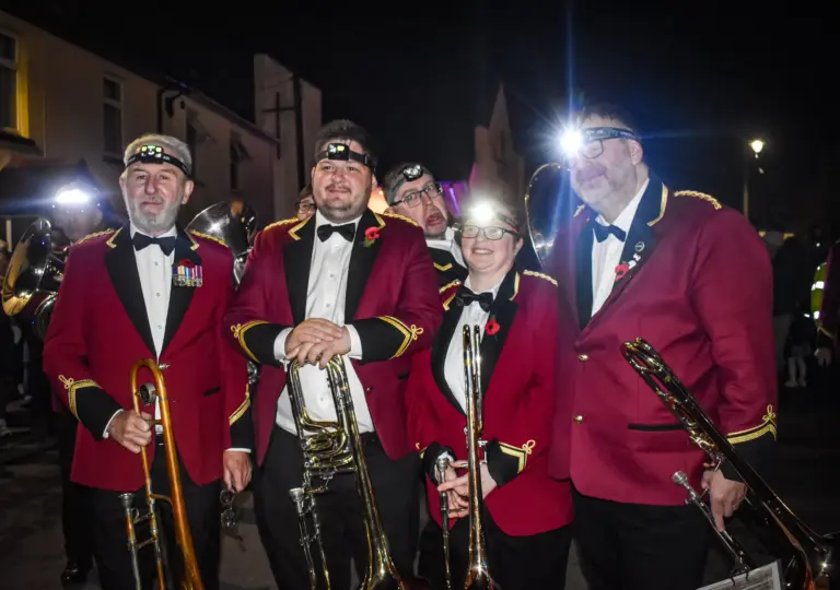 Members of the silver band in red jackets and bow ties holding their brass instruments