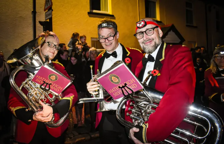 Brass band players in red jackets and headtorches holding euphonium and music