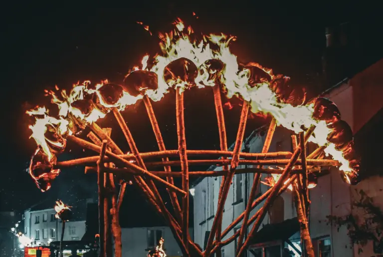 The giant wooden torch frame ablaze with flames against the night sky above the town
