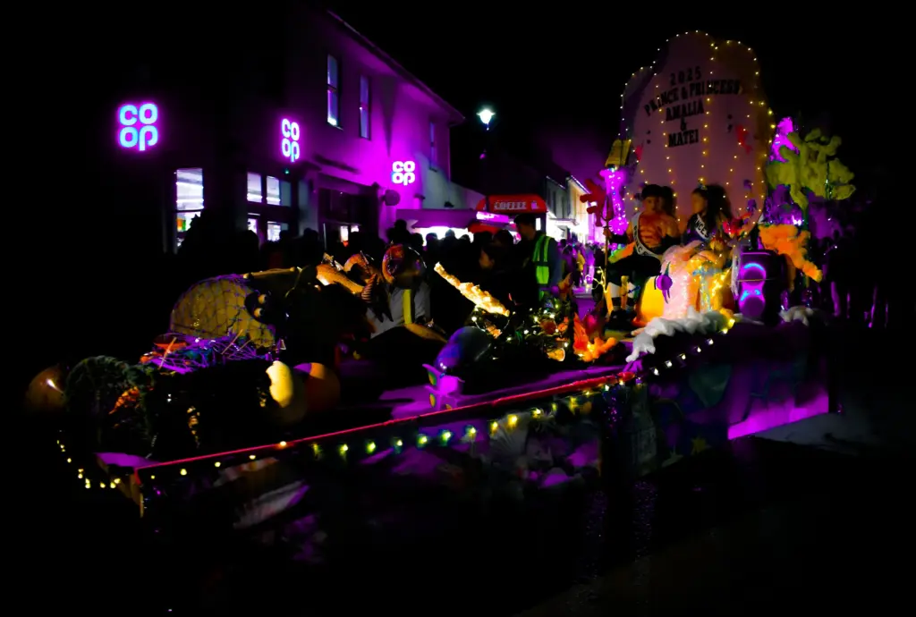 Float glowing purple and gold passing the Co-op on the high street at night