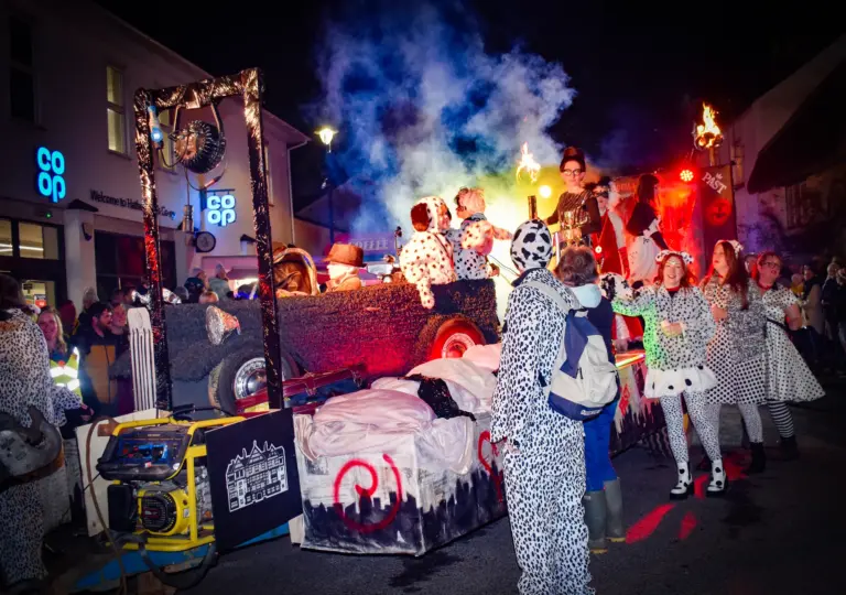 Dalmatian costumed entrants walking beside a smoky float past the Co-op