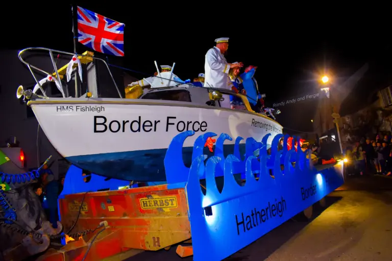 HMS Fishleigh Border Force boat float with a Union Jack rolling through the street