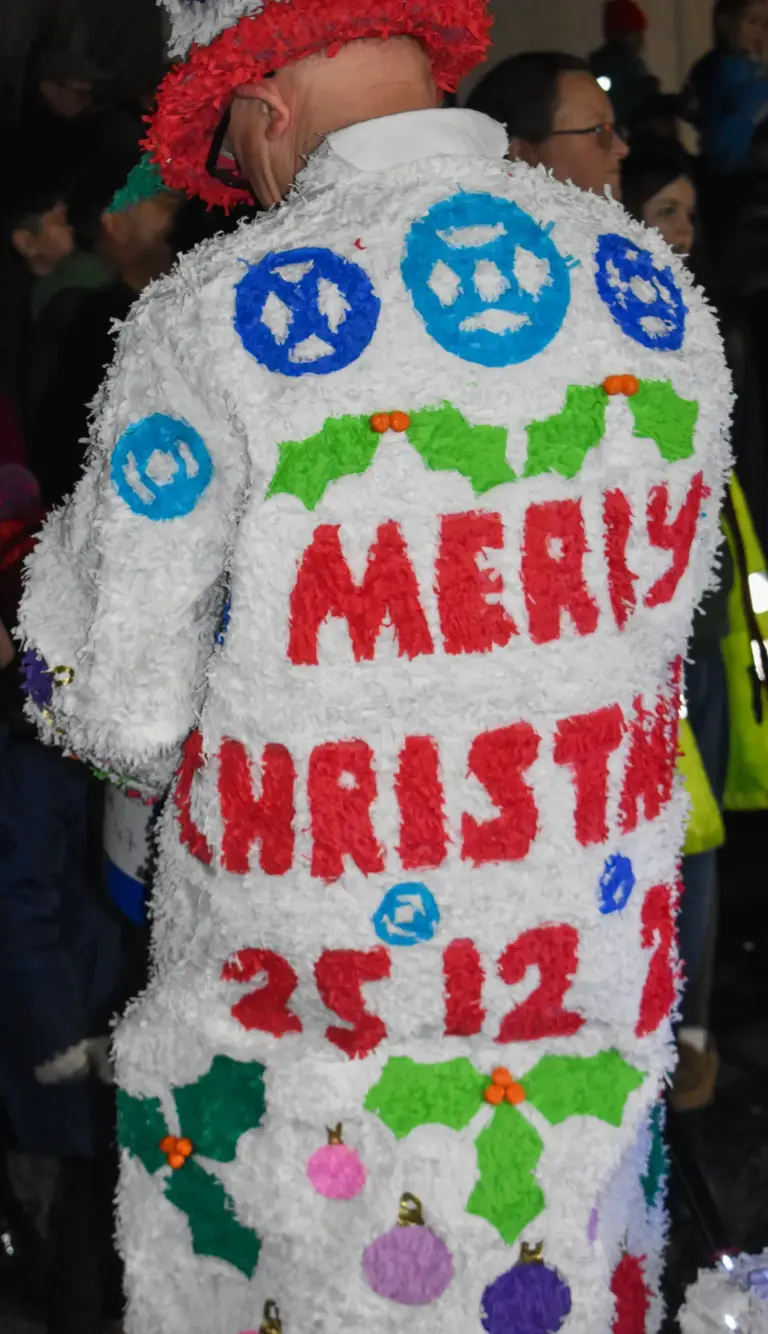 Back of a white costume decorated with Merry Christmas 25-12 in crepe paper