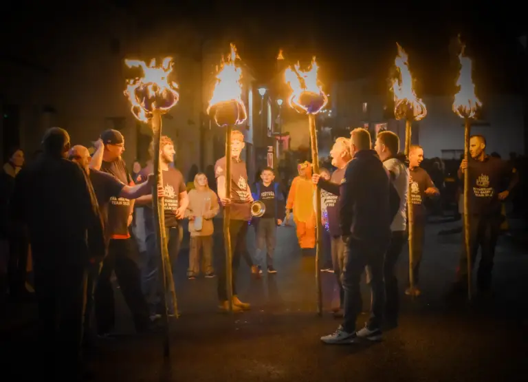 Tar Barrels Team members holding blazing torches aloft in the street at night before the Friday evening procession