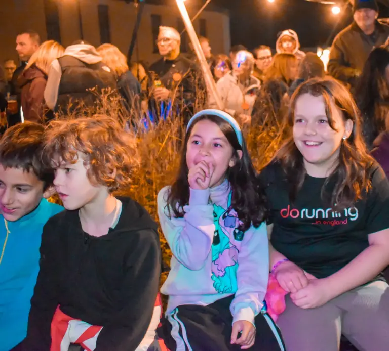 Children sitting together in the crowd laughing on carnival Friday evening