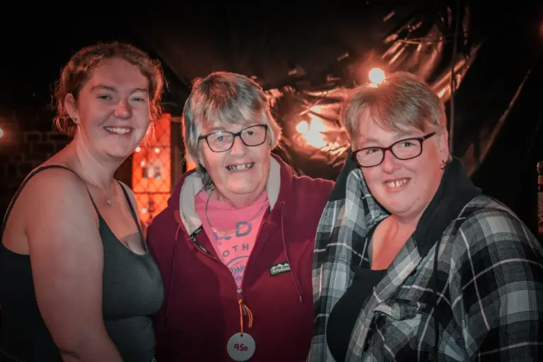 Three women smiling together at the carnival Friday evening gathering