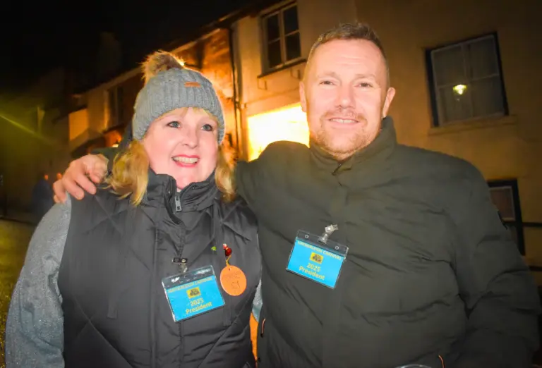 Two volunteers wearing lanyards smiling together on the street at night