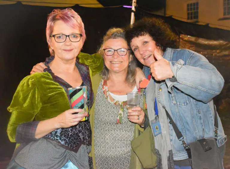 Three women laughing together, one giving a thumbs up, at the Friday evening event