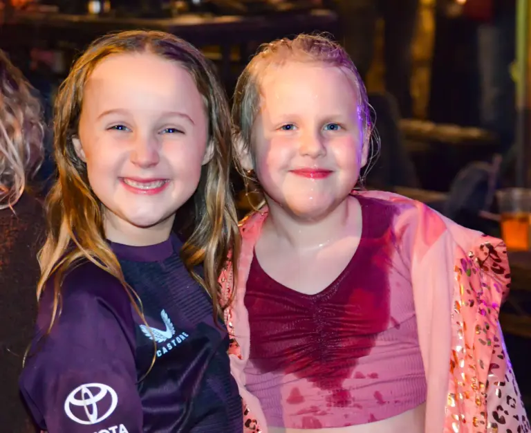 Two young girls smiling together at the Friday night live music