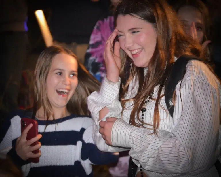 Two girls laughing together in the crowd on Friday evening