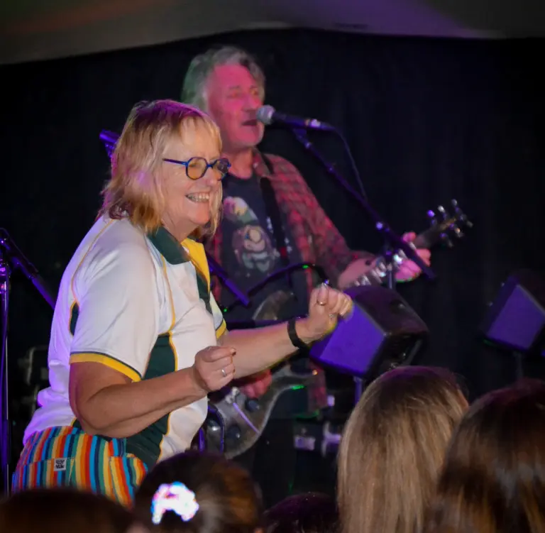 Woman in a rugby shirt dancing in front of a band playing live