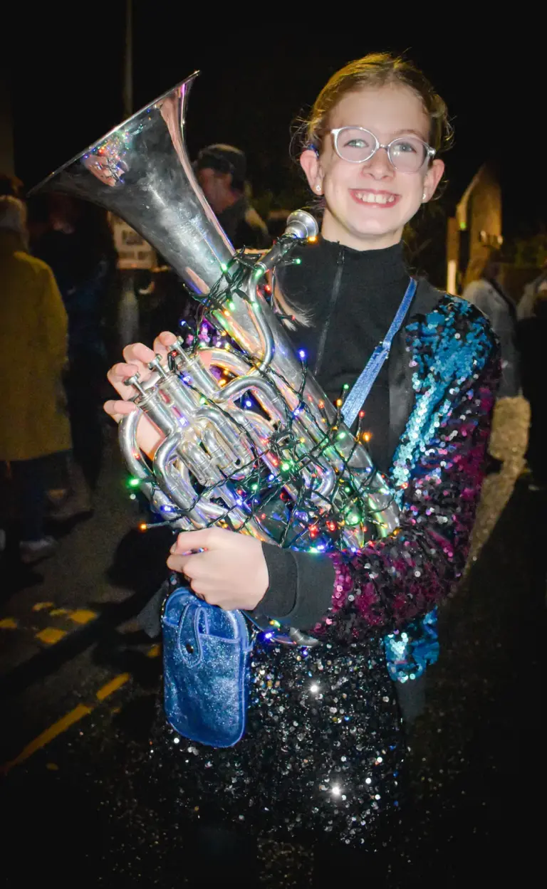 Smiling young musician in a sequin jacket holding a silver euphonium