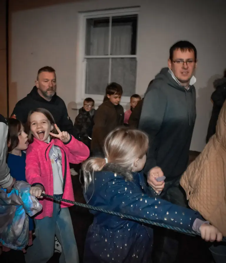 Children playing and pulling on a rope in the hall on Friday evening