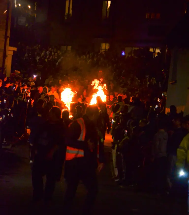 Burning tar barrels being rolled through the dark crowded street