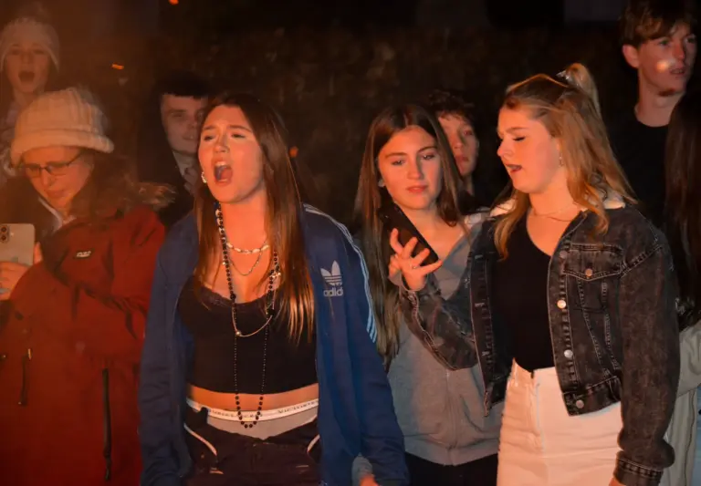 Teenage girls singing and cheering in the crowd at night
