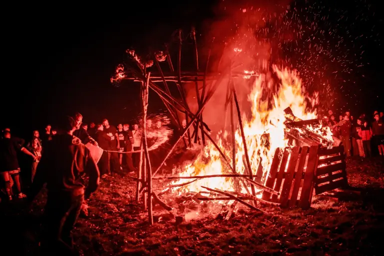 The bonfire burning fiercely with crowds silhouetted in the red glow