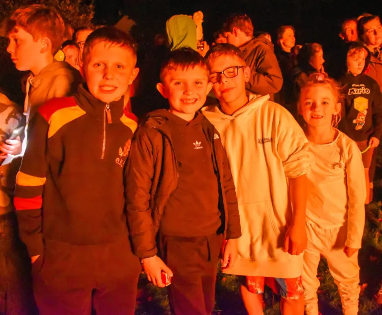Group of children lit orange by the bonfire smiling for the camera