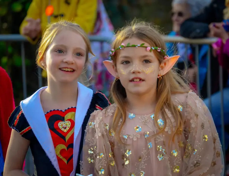Two girls dressed as a queen of hearts and a fairy with elf ears at the children's parade