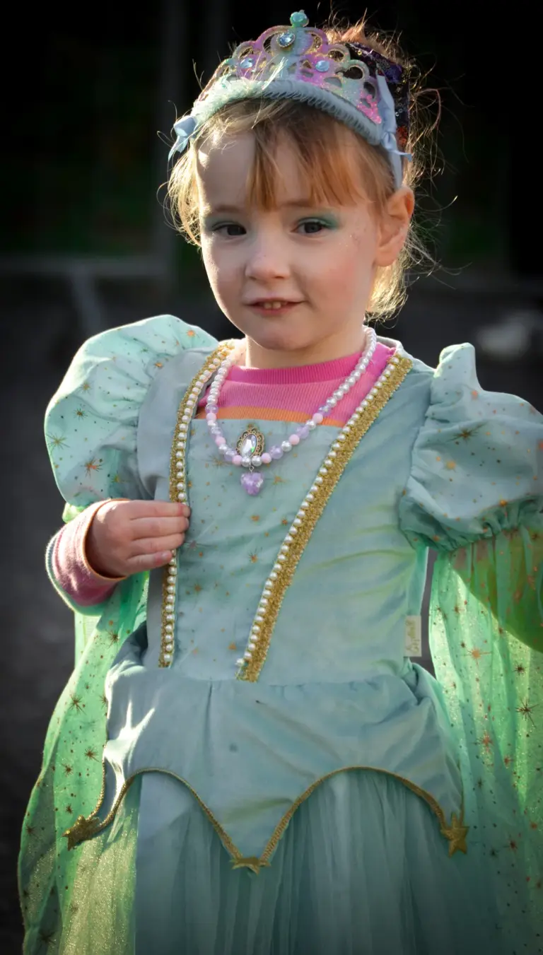 Toddler in a tiara, pearls and green princess dress at the children's parade