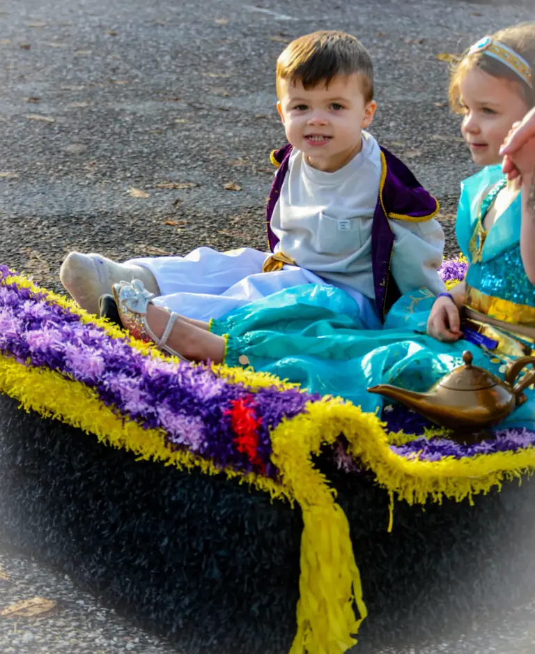 Young Aladdin and Jasmine sitting on their purple and yellow crepe-paper magic carpet