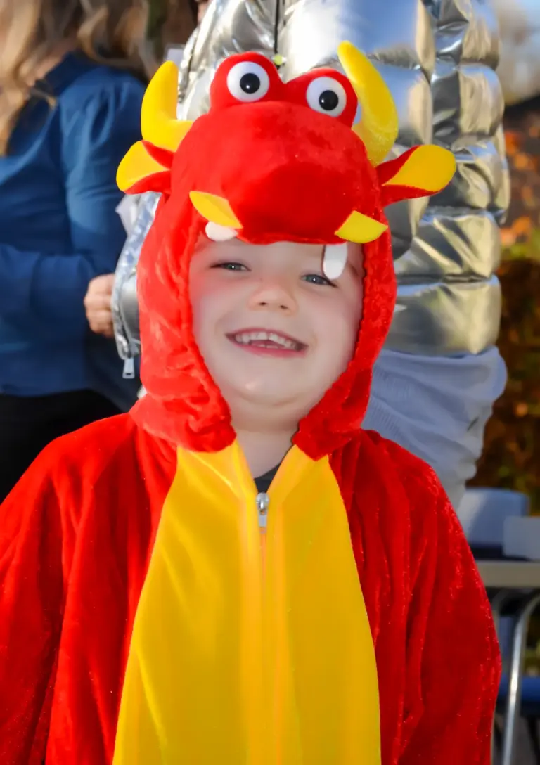 Smiling child in a red and yellow dragon onesie
