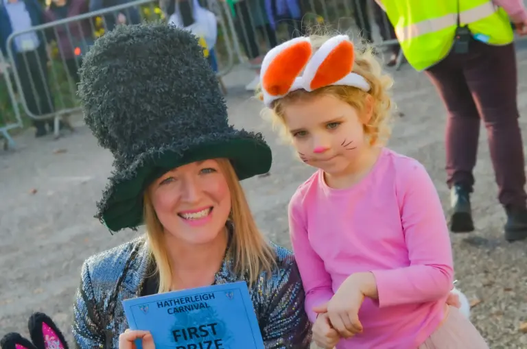 Woman in a giant top hat and a girl dressed as a cat holding a first prize card