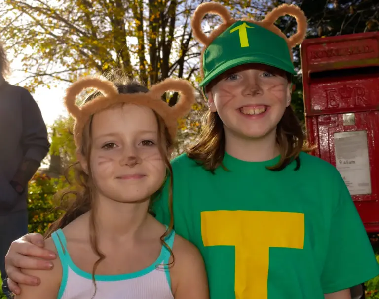 Two smiling girls with chipmunk ears, whiskers and a green T jersey