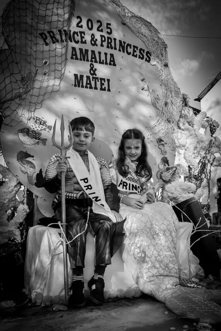 Black and white photo of the 2025 Carnival Prince and Princess seated on their under-the-sea float