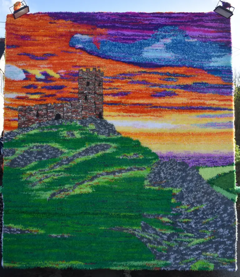 Crepe-paper artwork of a ruined tor tower against a fiery sunset on the queen's float