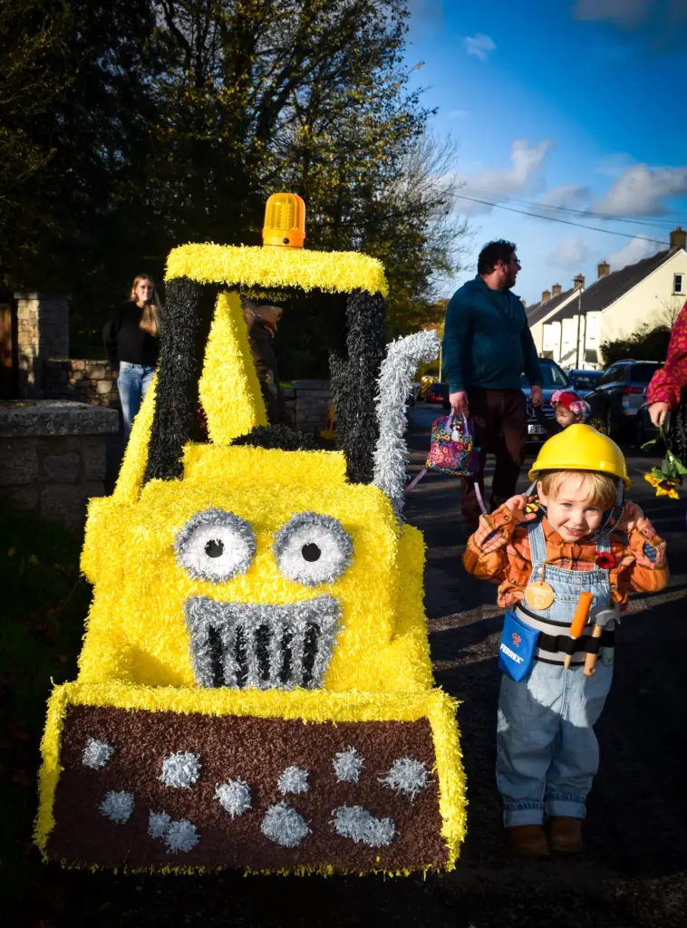 Toddler dressed as a builder beside a yellow crepe-paper digger
