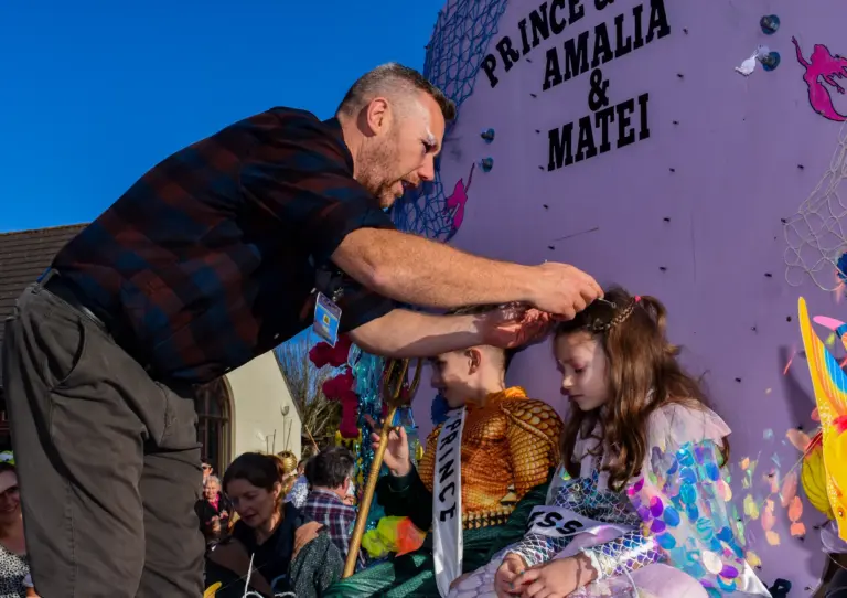 Man placing a tiara on the princess's head on the Prince and Princess float