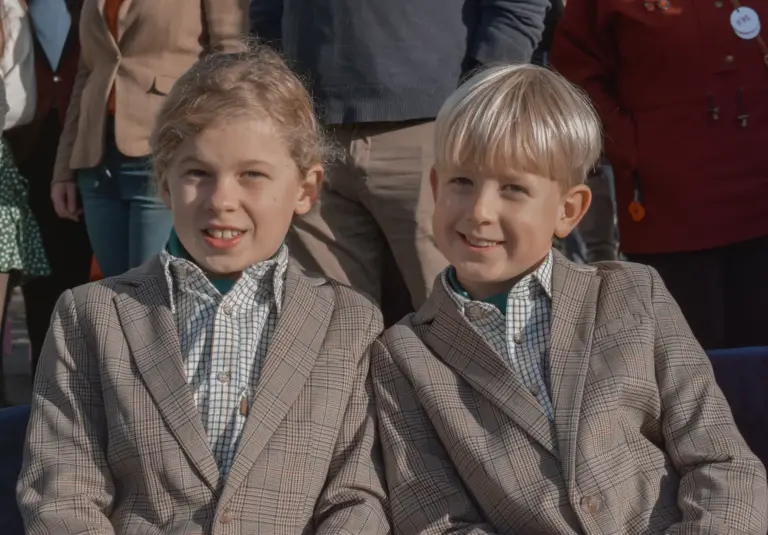 Two boys in tweed jackets and checked shirts smiling for the camera