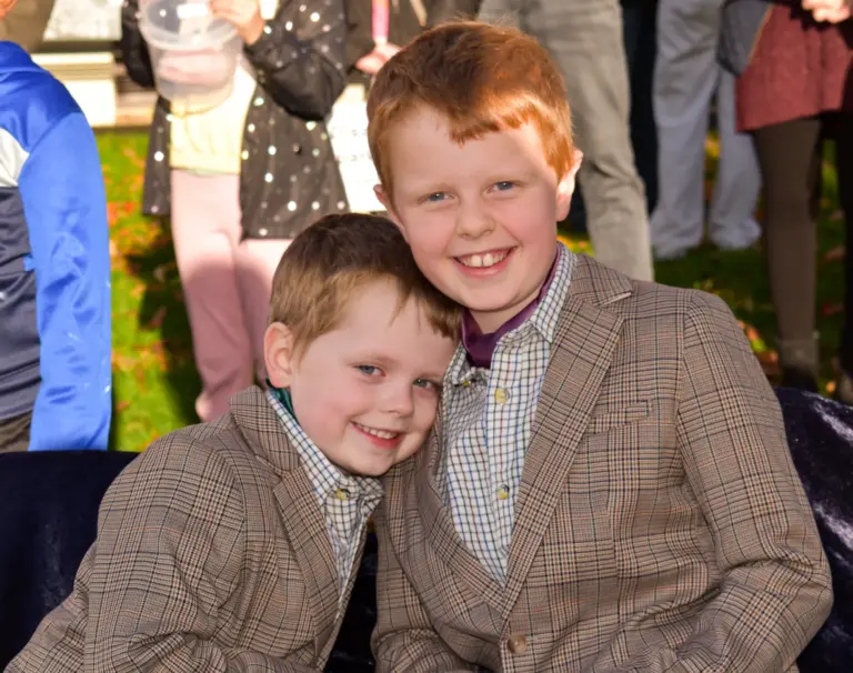 Two boys in tweed jackets hugging and smiling