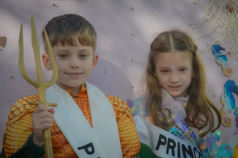 Close-up of the carnival prince holding a gold trident beside the princess
