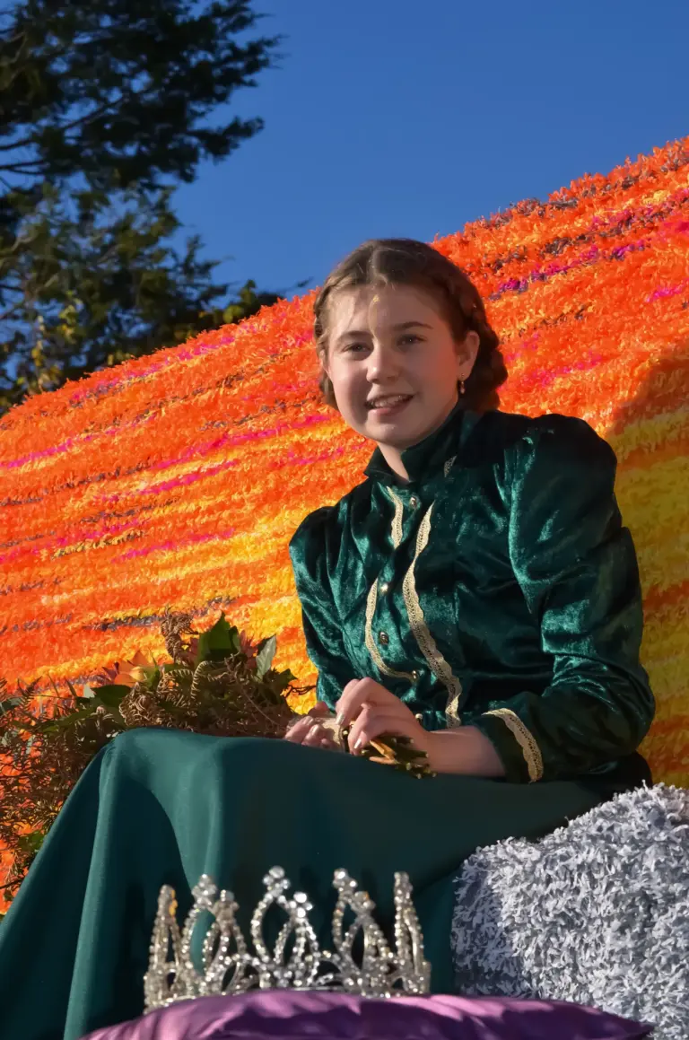 The carnival queen in green velvet seated on her float with her tiara beside her
