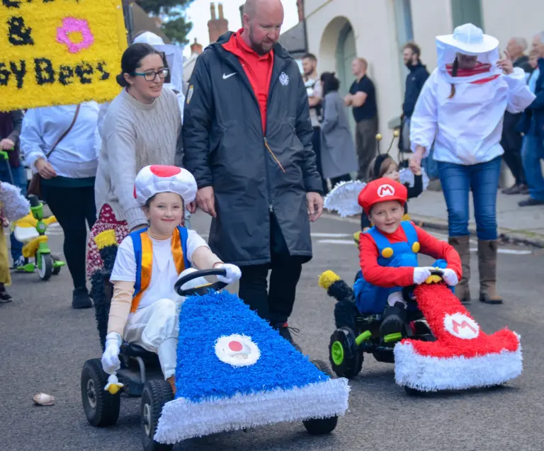 Children in Mario and Toad karts pushed along with the bee groups behind