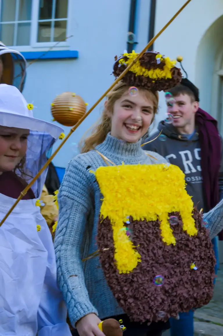 Smiling girl dressed as a dripping honey pot in the bee group