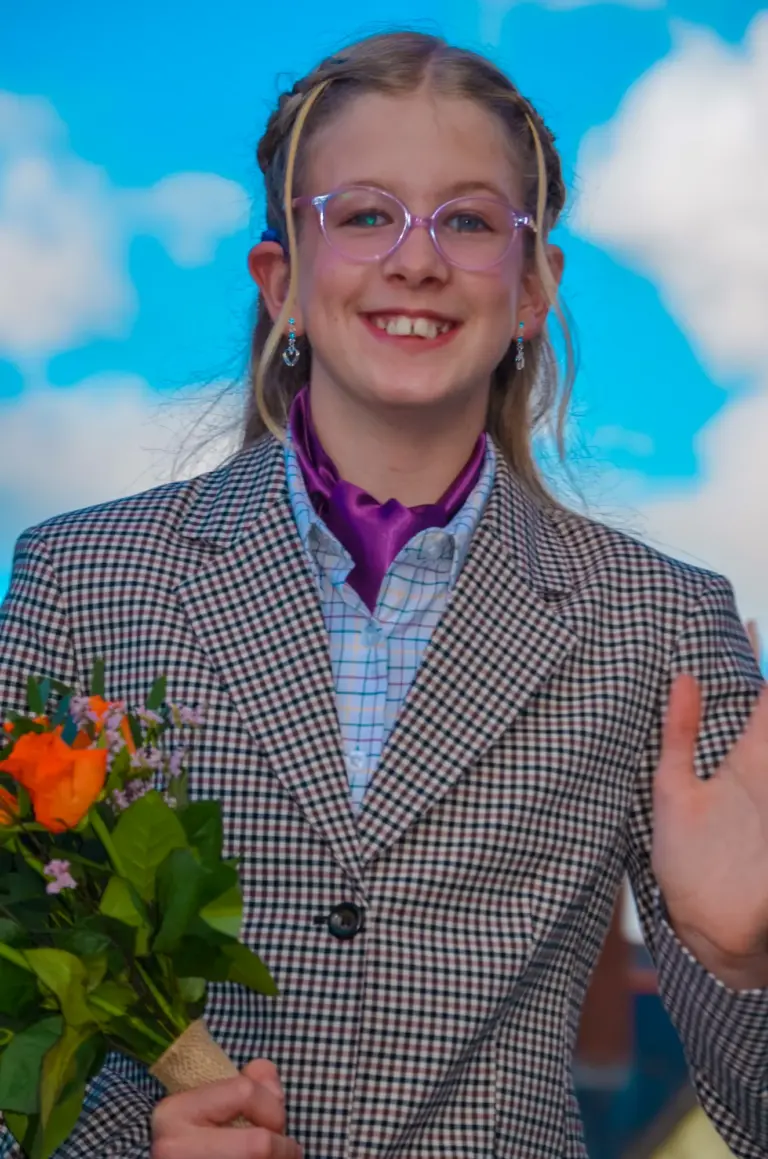 Girl in a tweed jacket and glasses waving with a bouquet of roses