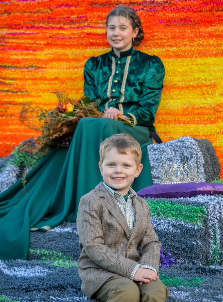 The carnival queen seated on her float with a young attendant in tweed
