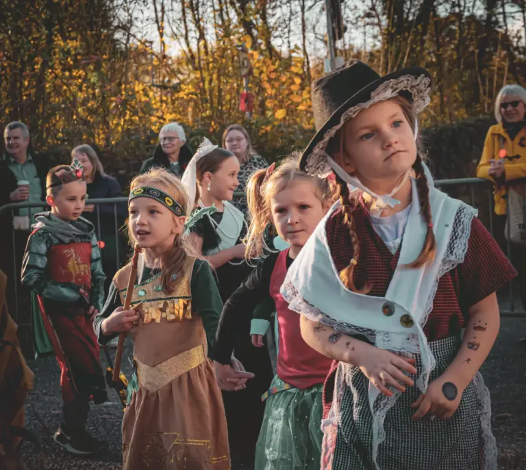 Children in historical costumes walking together in the parade