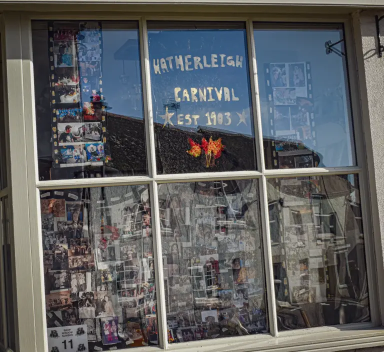 Shop window covered in carnival photographs with Hatherleigh Carnival est 1903