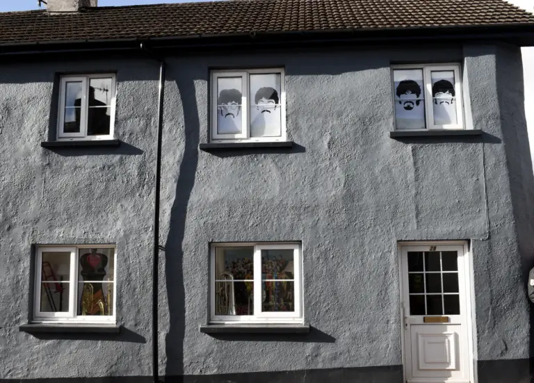 Grey rendered cottage with cartoon faces decorating its upstairs windows