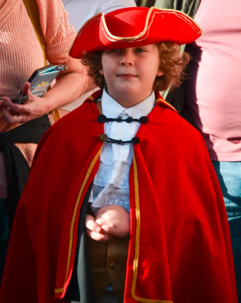 Child in a red tricorn hat and red cape with a lace jabot